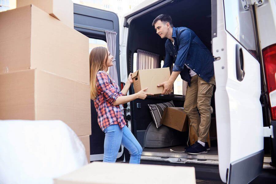 A man and woman holding the cardboard and placing them in a cargo van 