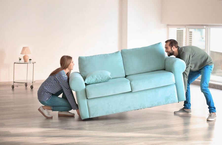 A man and woman are lifting their couch