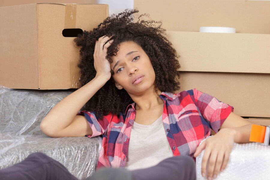 A girl holding her head while sitting with packages