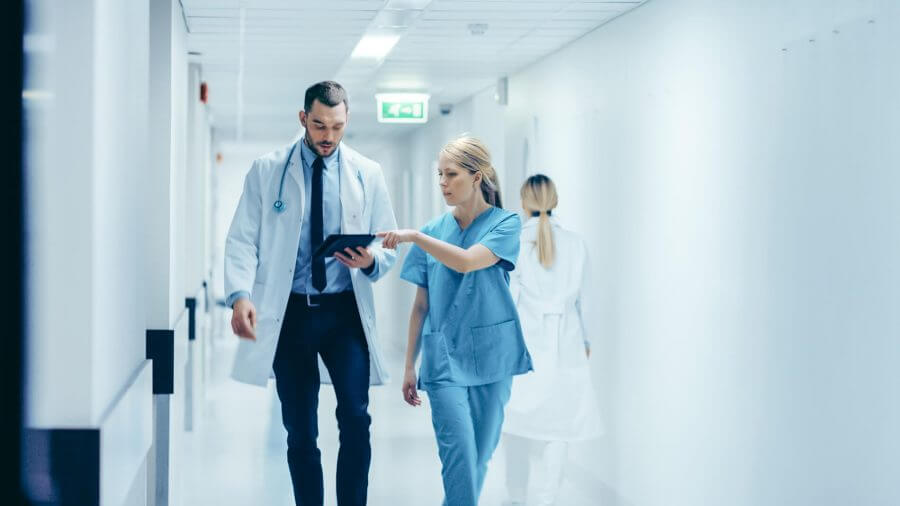 A doctor and a nurse walking down a hospital hallway