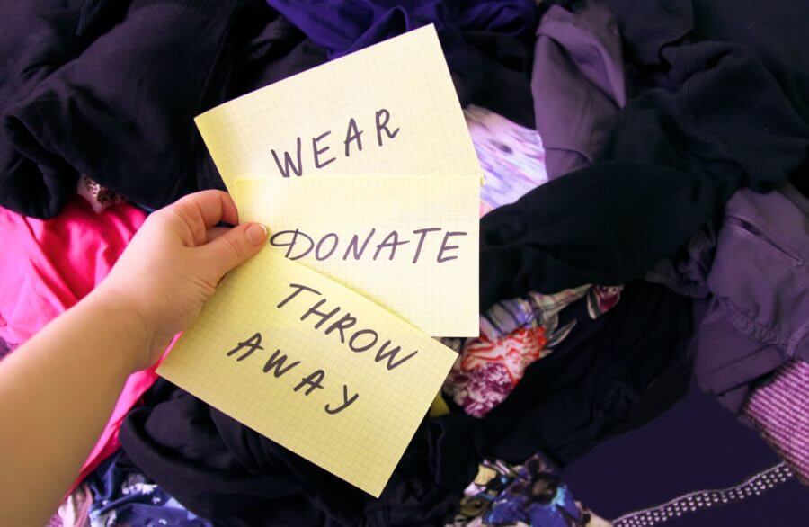 A person holding papers with wear, donate, and throw away signs