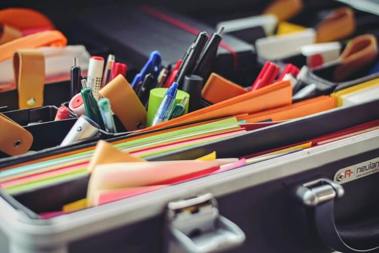 Office supplies like pens and papers packed messily into an organizer