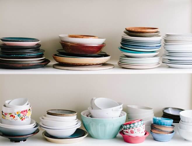 Many colorful sorted dishes and plates on shelves