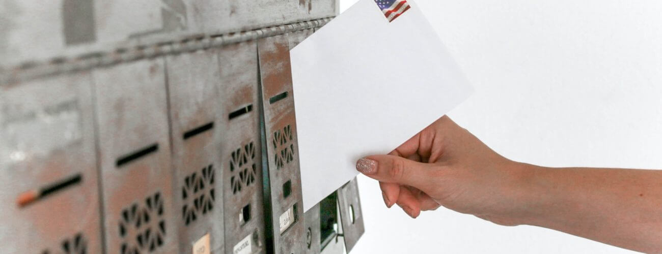 A person putting a white envelope in a mailbox