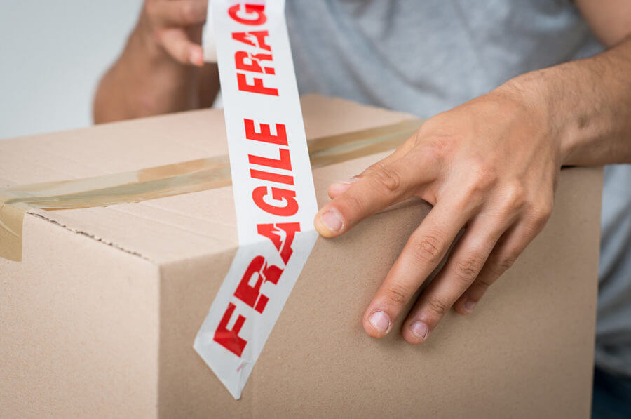 man sticking a box label for cross-country moving