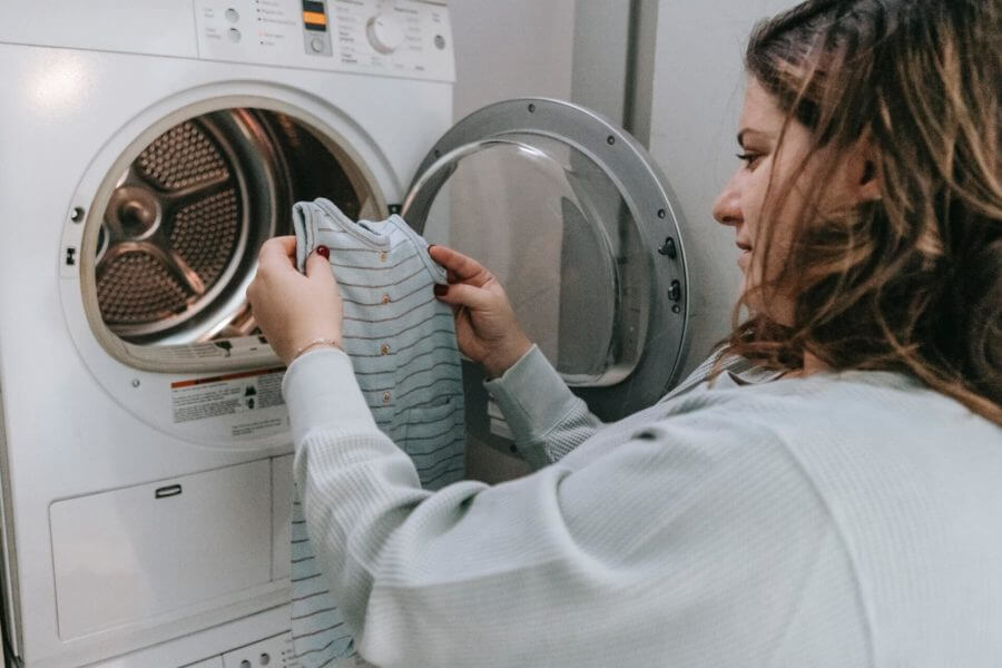 A woman taking baby clothes out of the dryer