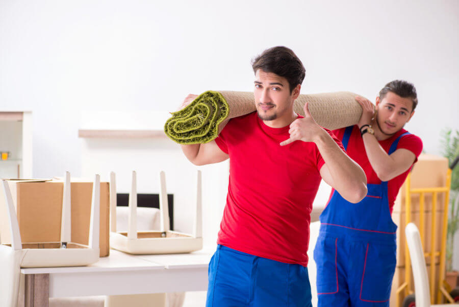 Two cross-country movers carrying a carpet