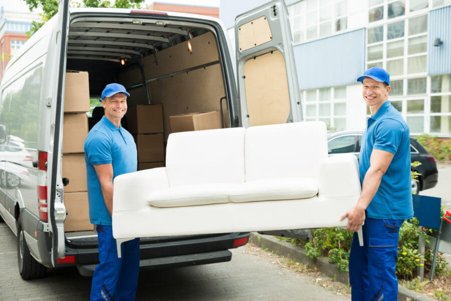Two cross-country movers loading a sofa onto a truck