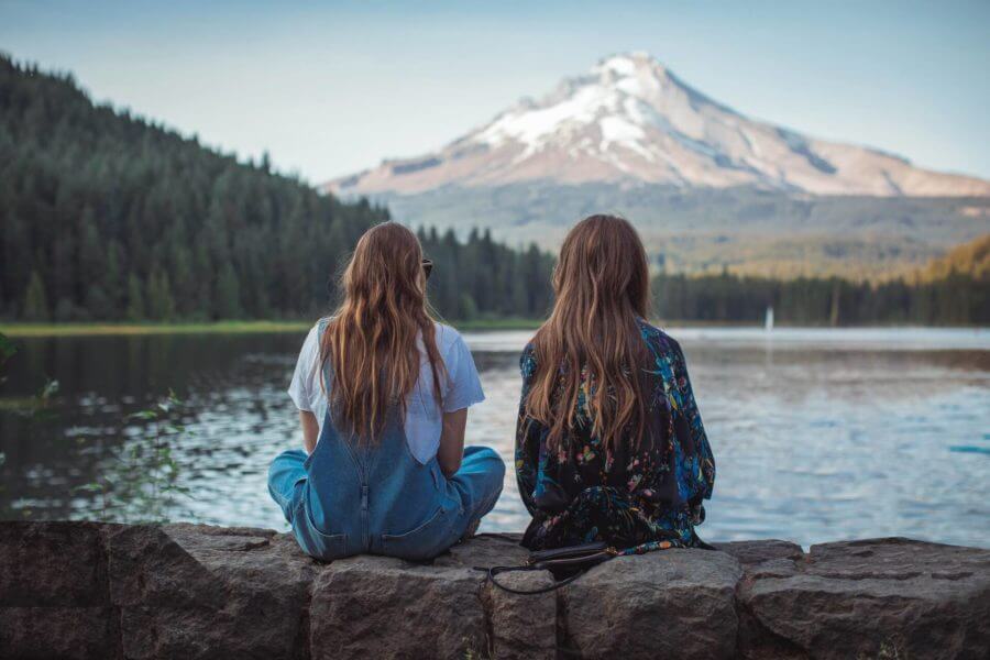 two friends sitting in front of a lake and sightseeing after cross-country moving