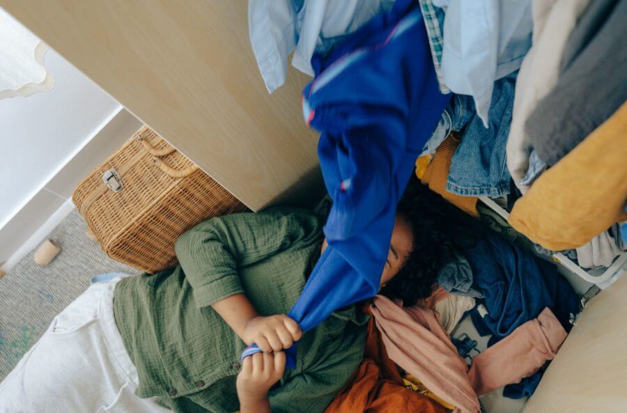A girl laying in the pile of clothes before cross-country moving