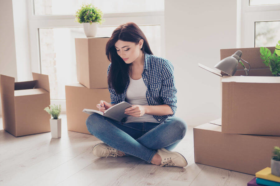 A young woman taking notes surrounded by boxes