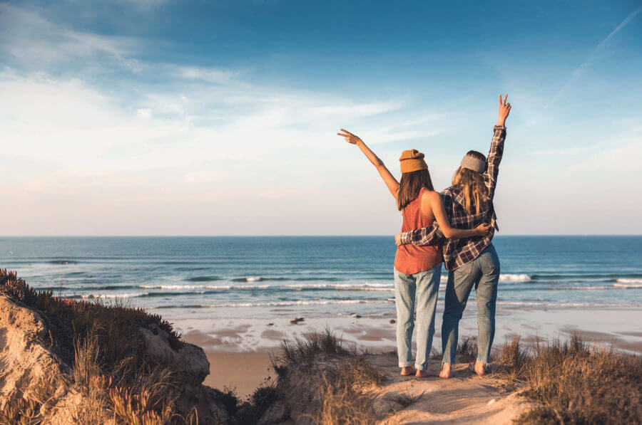 two girls hugging and standing on a beach after cross-country moving