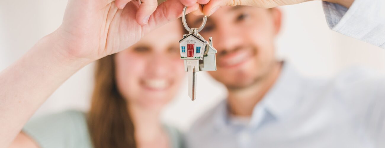 A couple holding house keys for sale