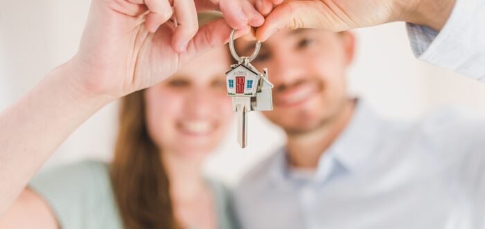 A couple holding house keys for sale