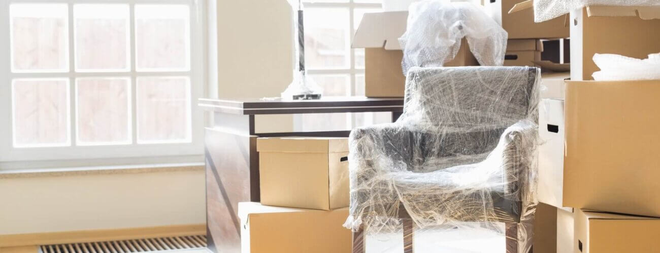 A chair wrapped in plastic and boxes stacked on top of each other behind it