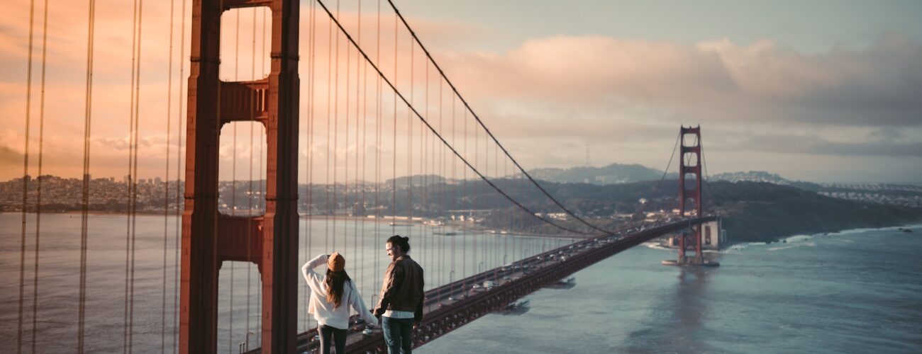 A couple holding hands next to The Golden Gate Bridge after moving across the country