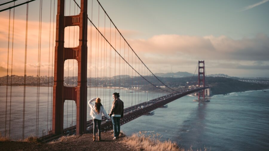 A couple holding hands next to The Golden Gate Bridge after moving across the country