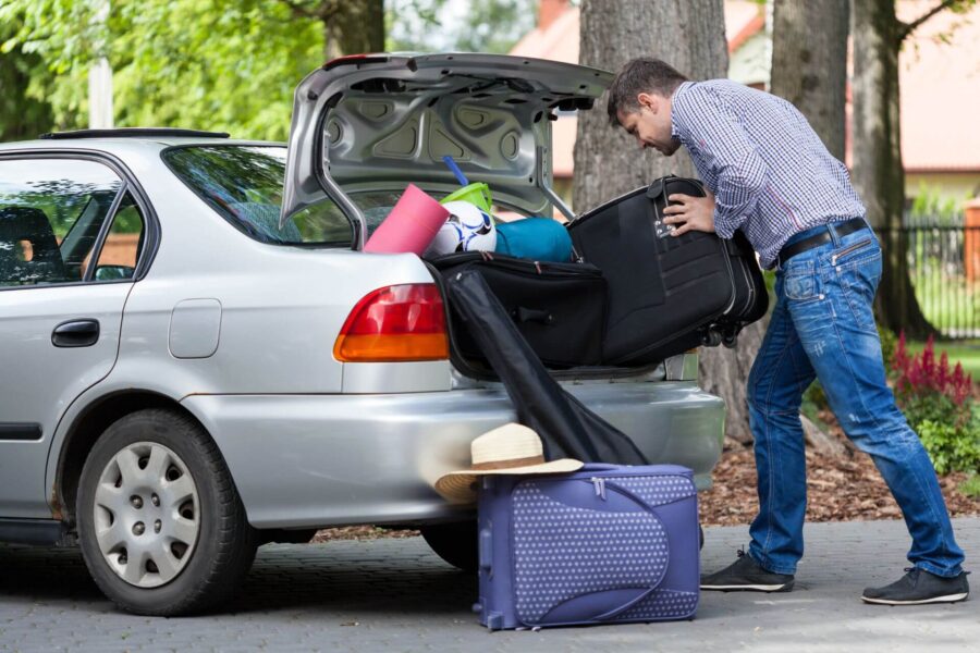 A man packing his stuff in the back of the car
