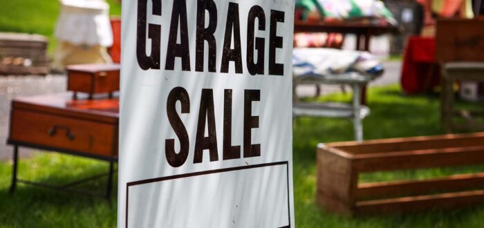 Garage sale sign on the lawn of a suburban home