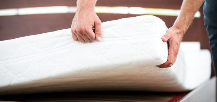 Close-up photo of a young man demonstrating the quality of a mattress