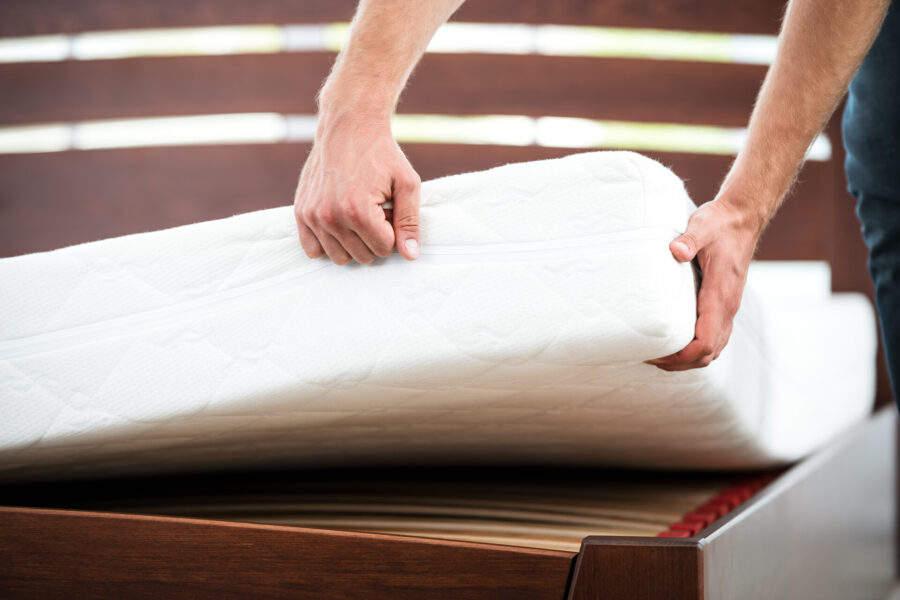 A person lifting a mattress off the bed