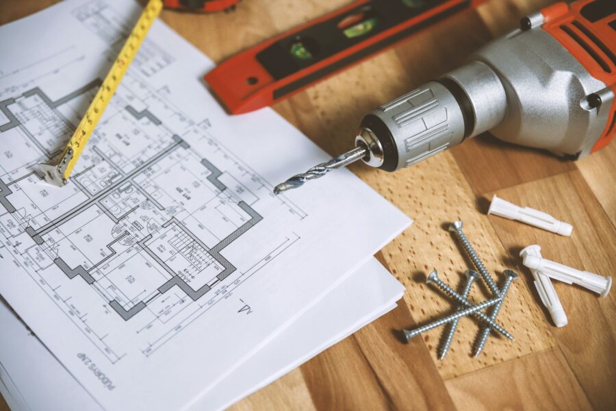 Tools and a floor plan on a wooden surface