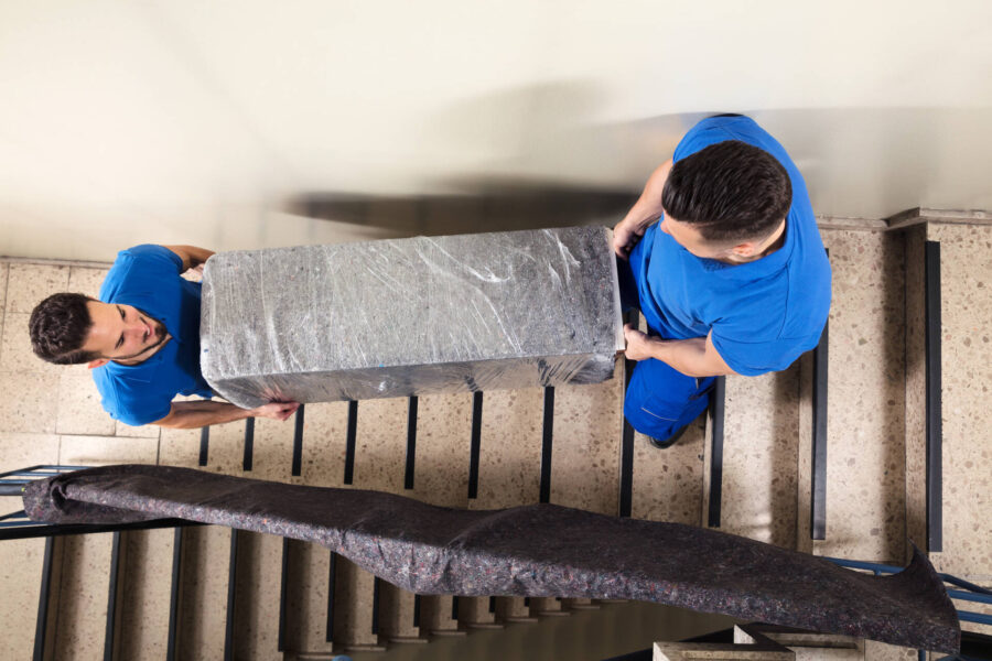 Two movers carrying a large object down some stairs