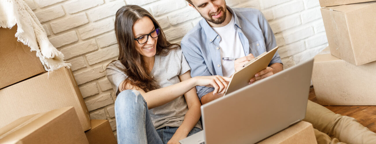 Man and woman looking at a to-do list for long-distance moving with a laptop next to them
