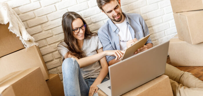 Man and woman looking at a to-do list for long-distance moving with a laptop next to them