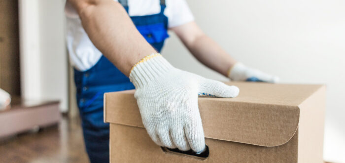 A mover with gloves holding a box