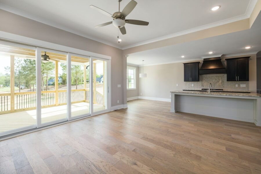 An empty house with a wooden floor and a big ceiling fan