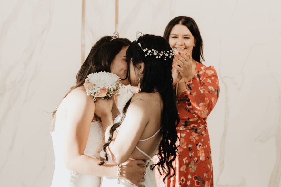 a couple of women in red and white floral dresses getting married