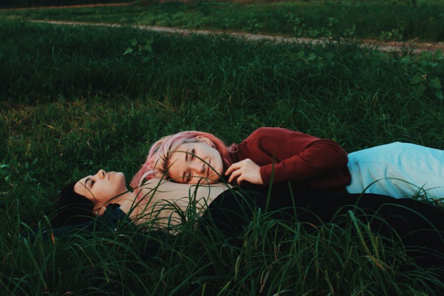 a couple of women lying on green grass
