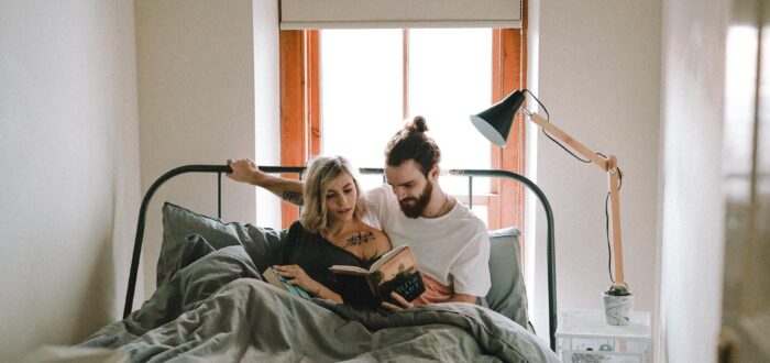 A couple reading in bed after long-distance moving