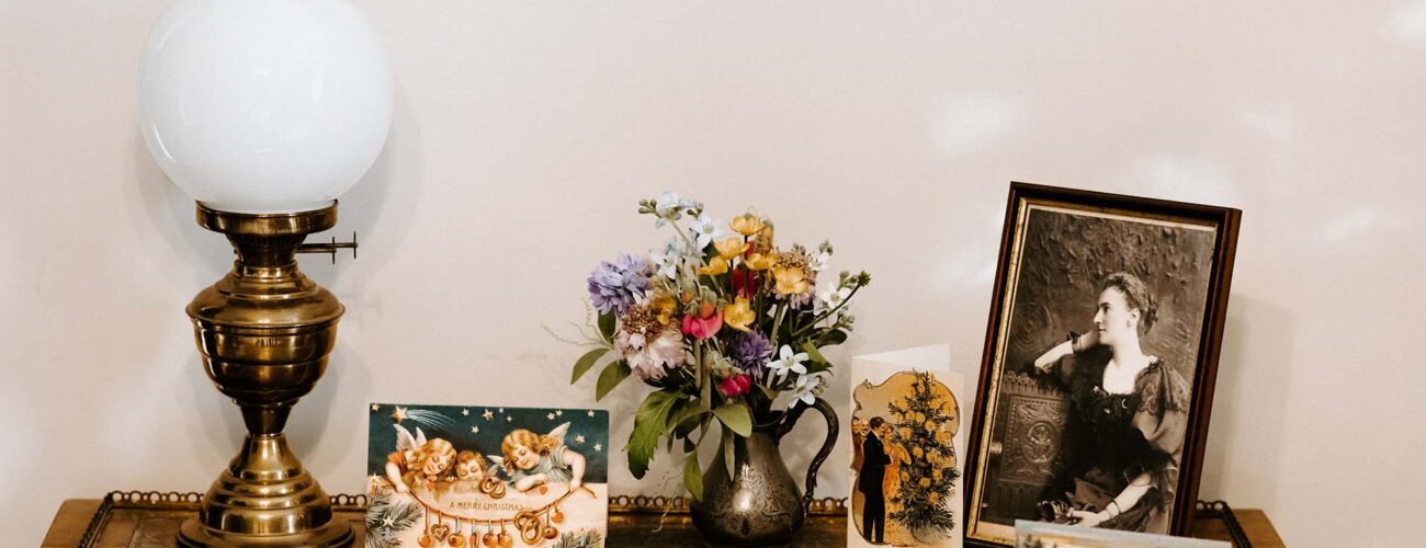 An antique lamp, photos, and flowers on a desk