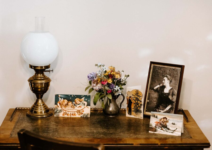 An antique lamp, photos, and flowers on a desk