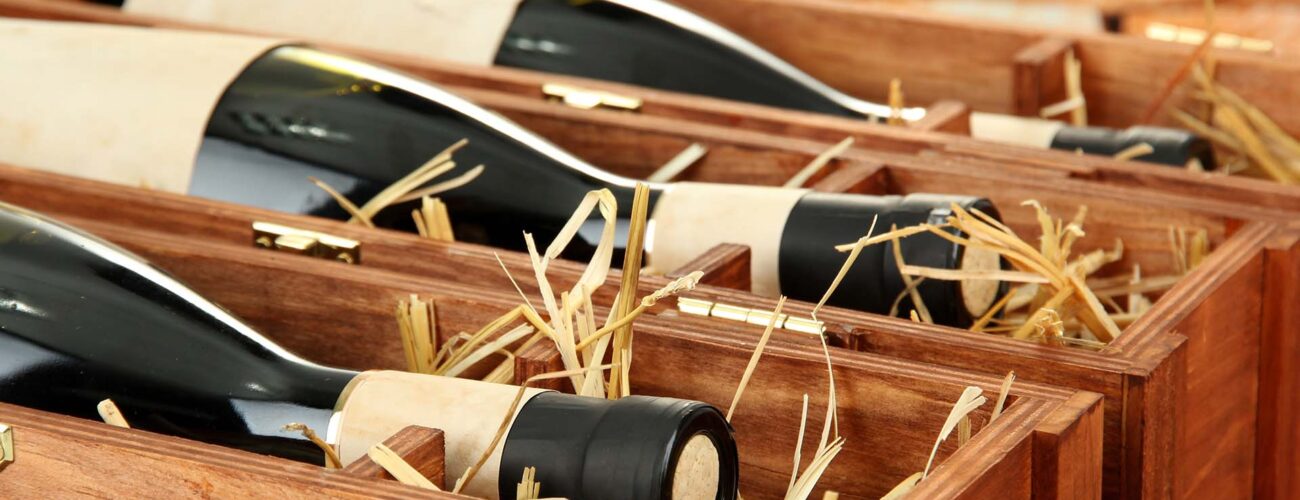 Bottles of old red wine in gift wooden box, on stone background