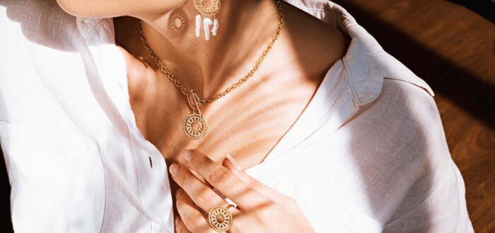 A woman in a white shirt wearing a necklace, earrings, and a ring