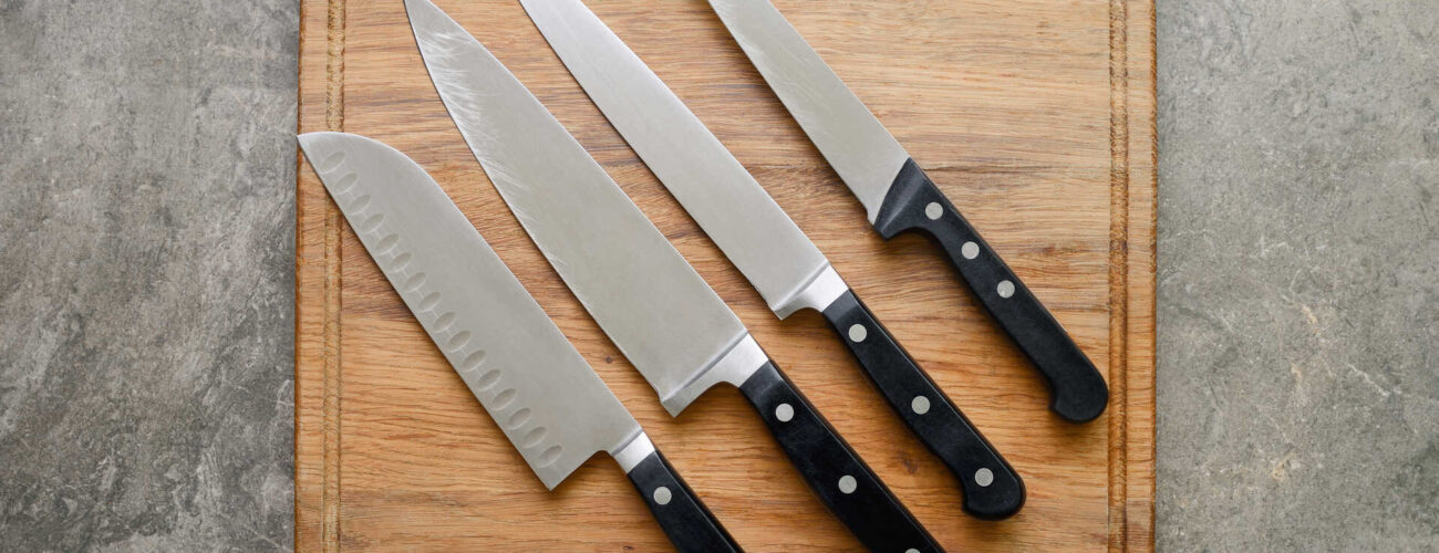Five kitchen knives on a white wooden board