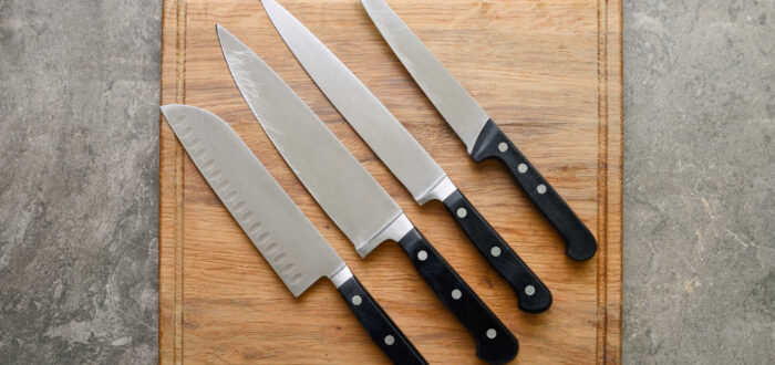 Five kitchen knives on a white wooden board
