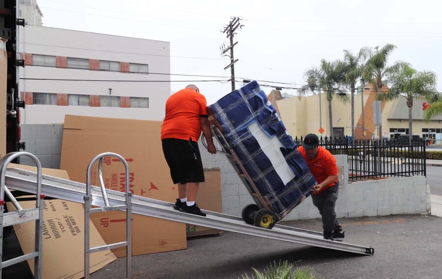 Two cross-country movers loading a large item onto the truck