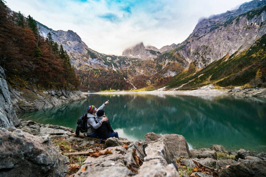 A couple sitting on a lake surrounded by mountains