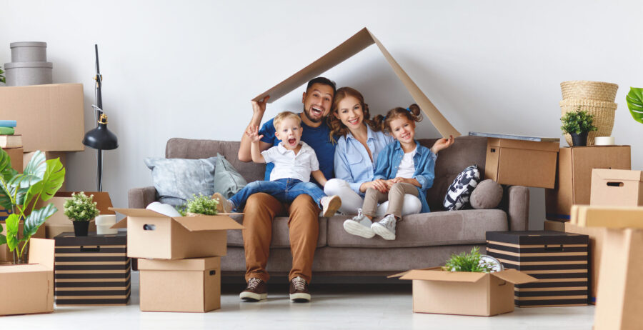 A happy family sitting on the couch with boxes around them 