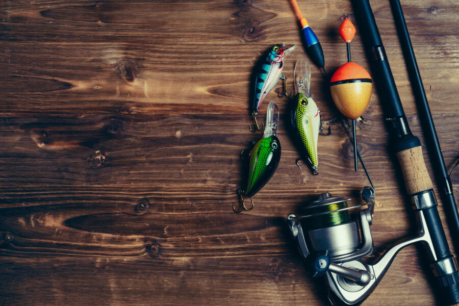 Lures next to a fishing rod on a wooden surface