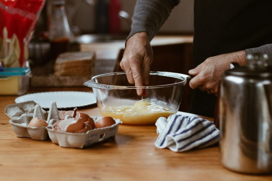 A person mixing eggs in a glass bowl