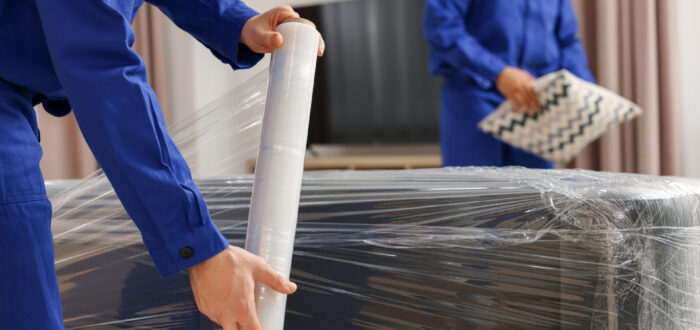 Professional movers wrapping a couch for transport