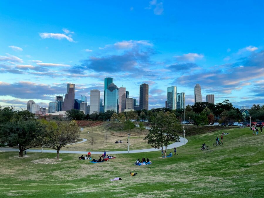 People relaxing on grass in a downtown Houston park.